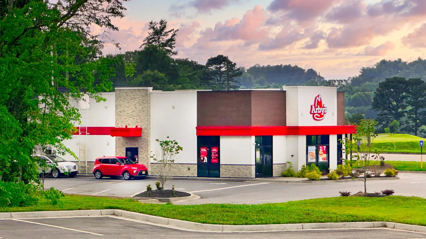 An Arby's restaurant beside a road at dusk
