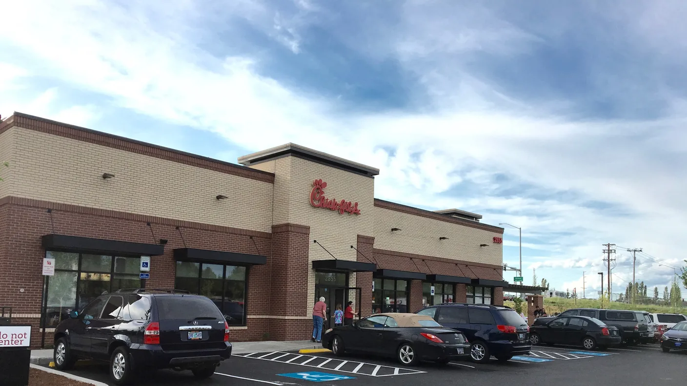 A Chick-fil-A restaurant behind a full parking lot