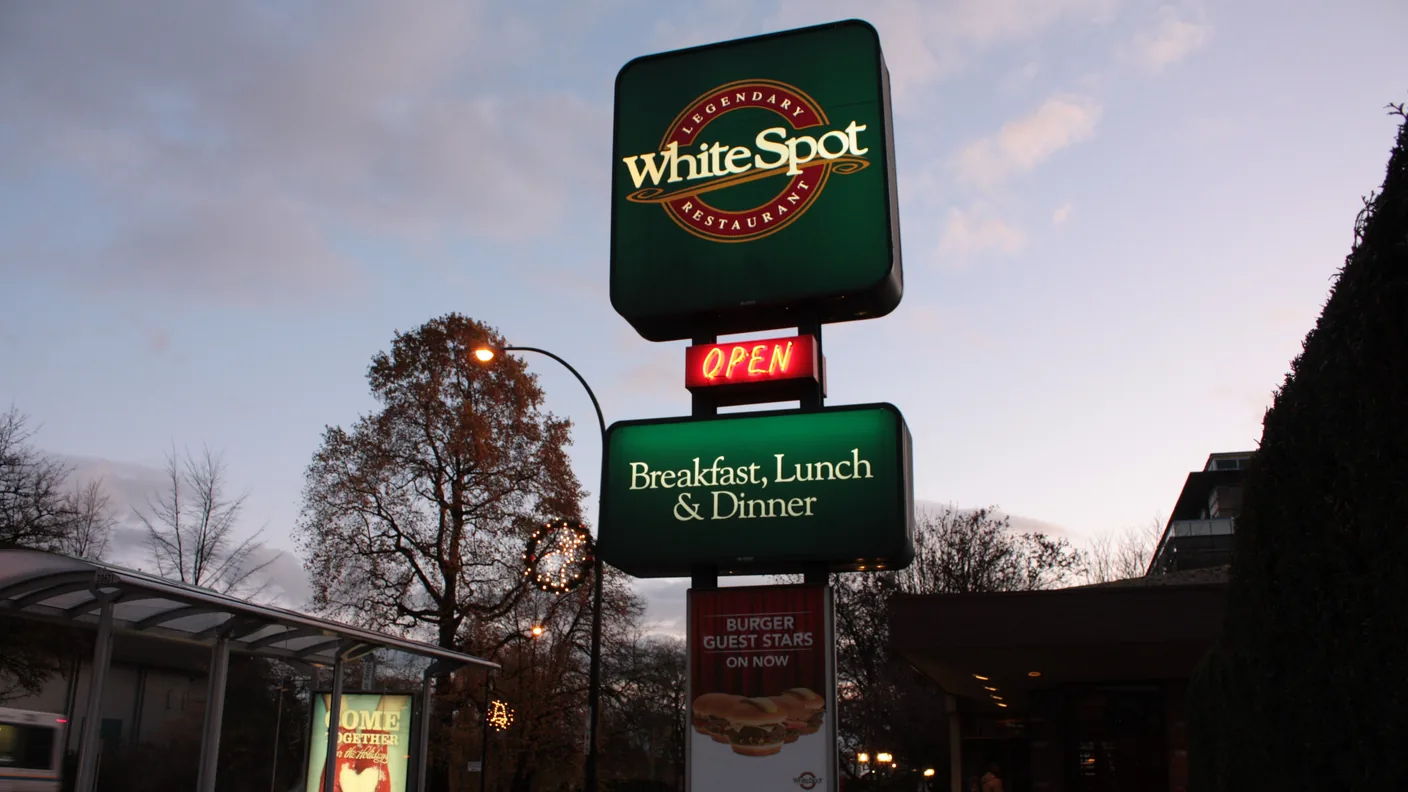 A lit White Spot pylon sign at dusk